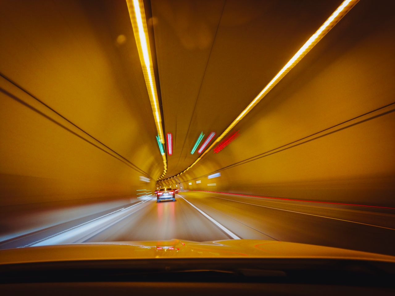 Services Blurry traffic scene with cars speeding through a brightly lit tunnel at night.