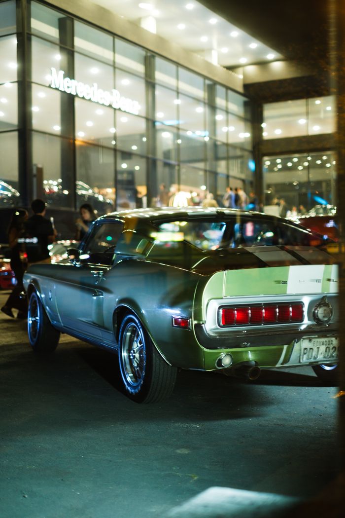 Services Classic Ford Mustang in moody night setting outside a showroom.